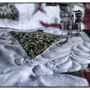 Close up photo of sewing machine doing free motion quilting.  